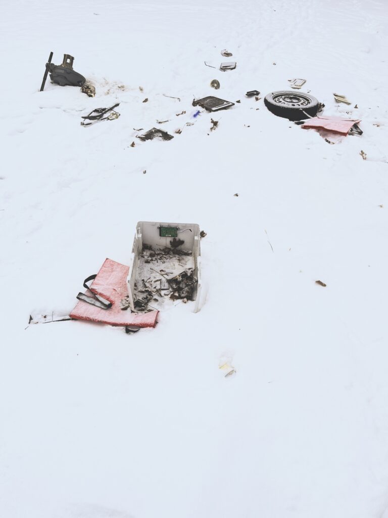 Photo of random large garbage objects strewn on the snowy ground