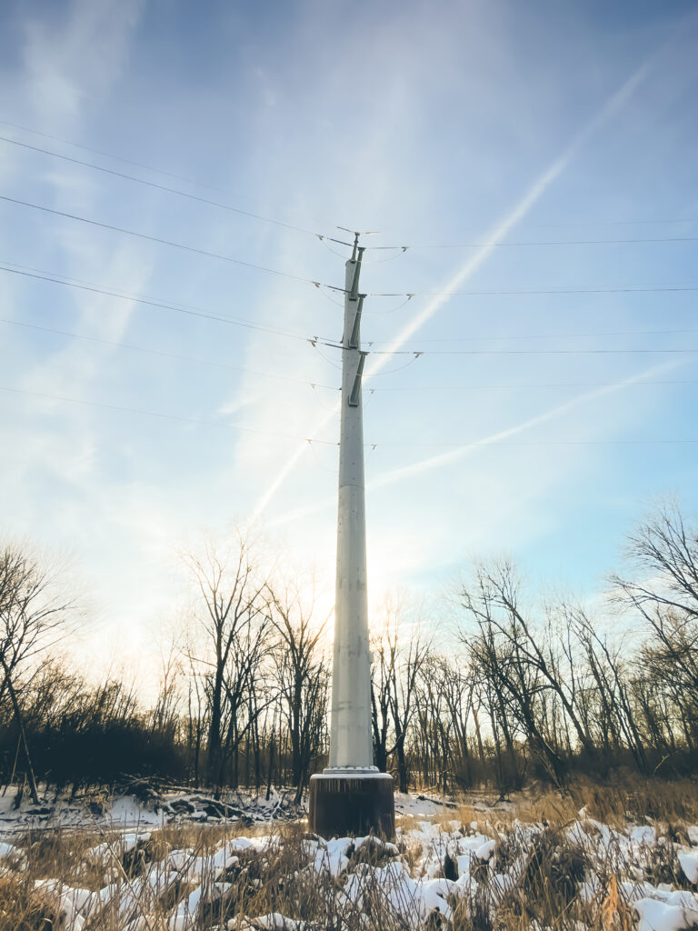 Photo of a large electric pole in winter backlit by the rising sun